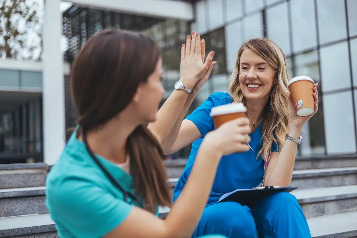 Two healthcare professionals high fiving while on a coffee break