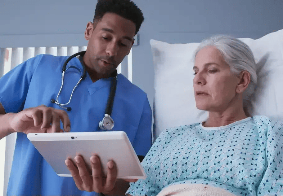 Registered nurse showing a patient a tablet while in a hospital