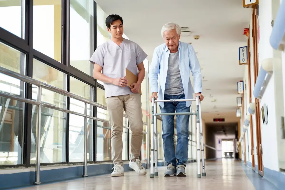 Occupational therapist helping an elderly patient learn how to walk again