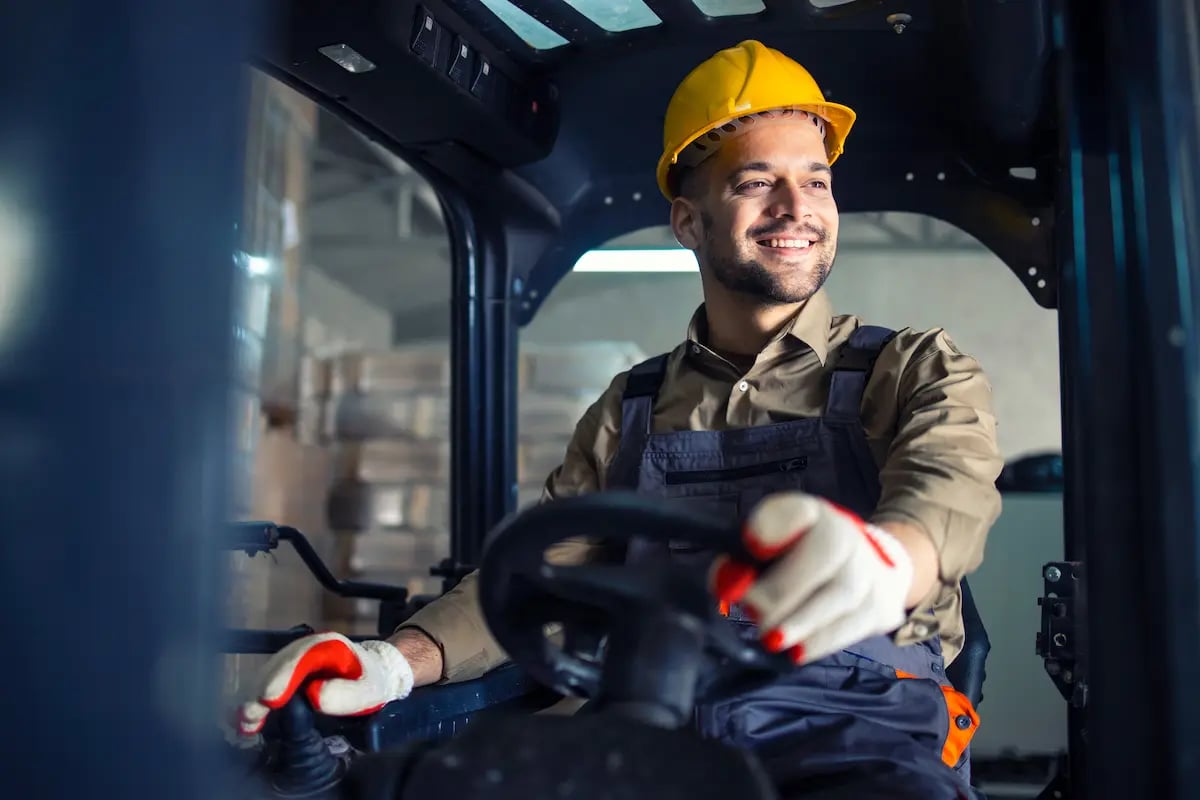 Non-clinical worker smiling and driving a forklift at a hospital warehouse