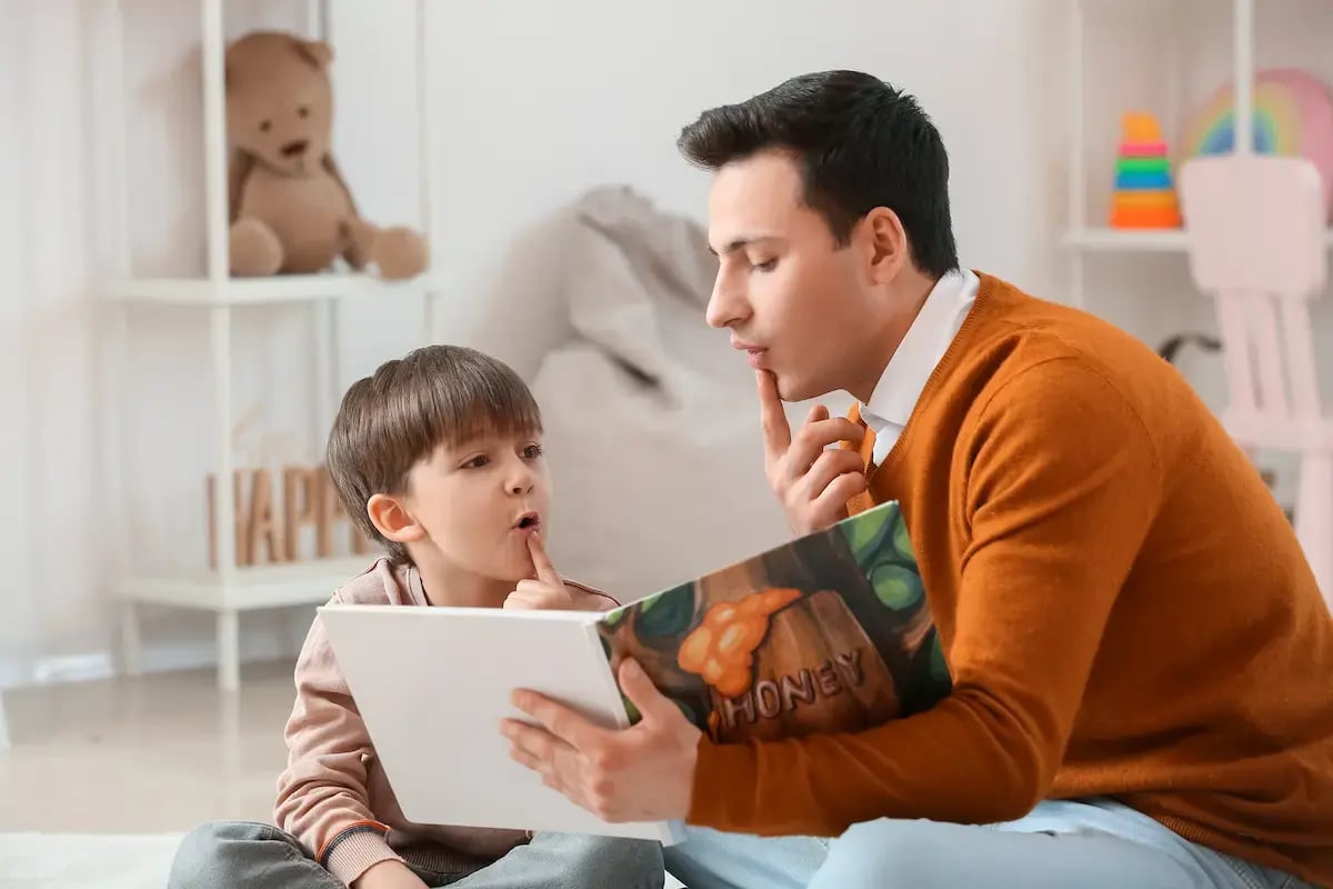 Speech therapist helping a young patient pronounce words in a book