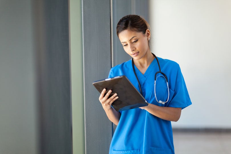 A nurse on the job reading a clipboard