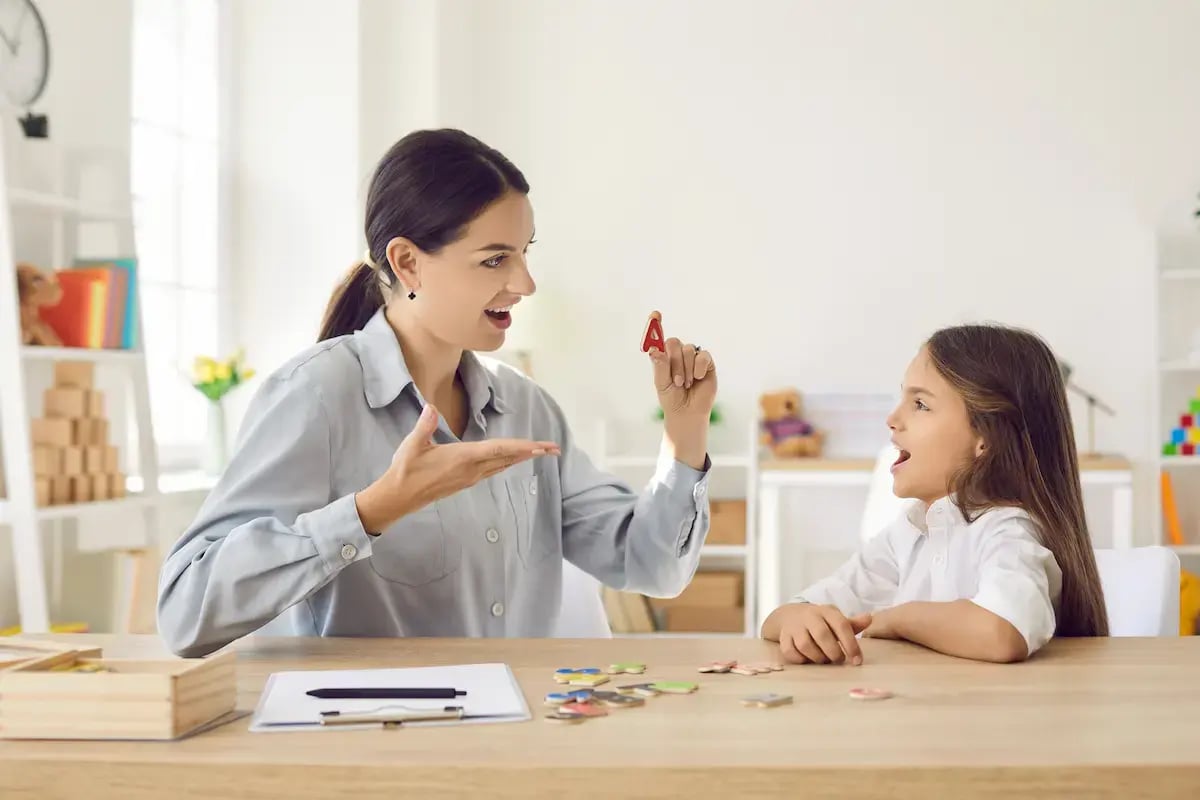 Speech therapist showing the letter A to a young patient