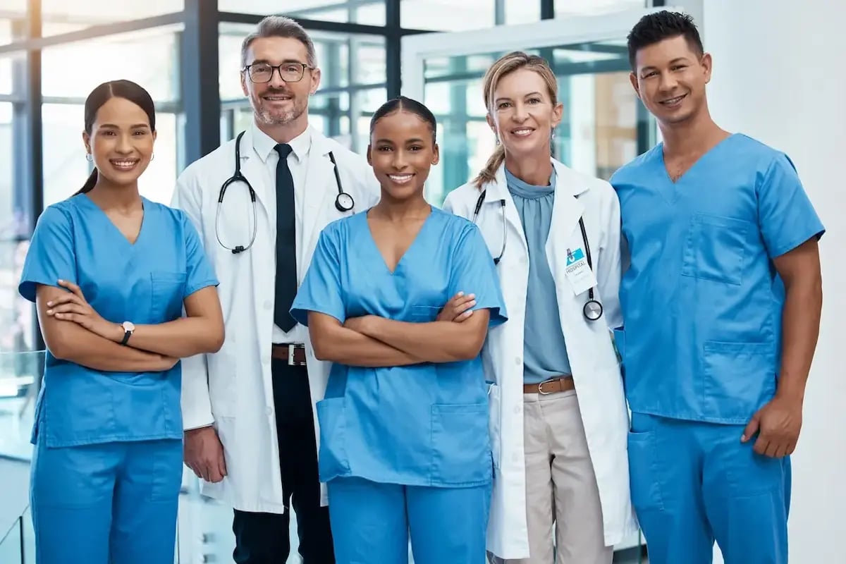 Group of nurse practitioners and physicians smiling while in a hospital lobby Group of nurse practitioners and physicians smiling while in a hospital lobby