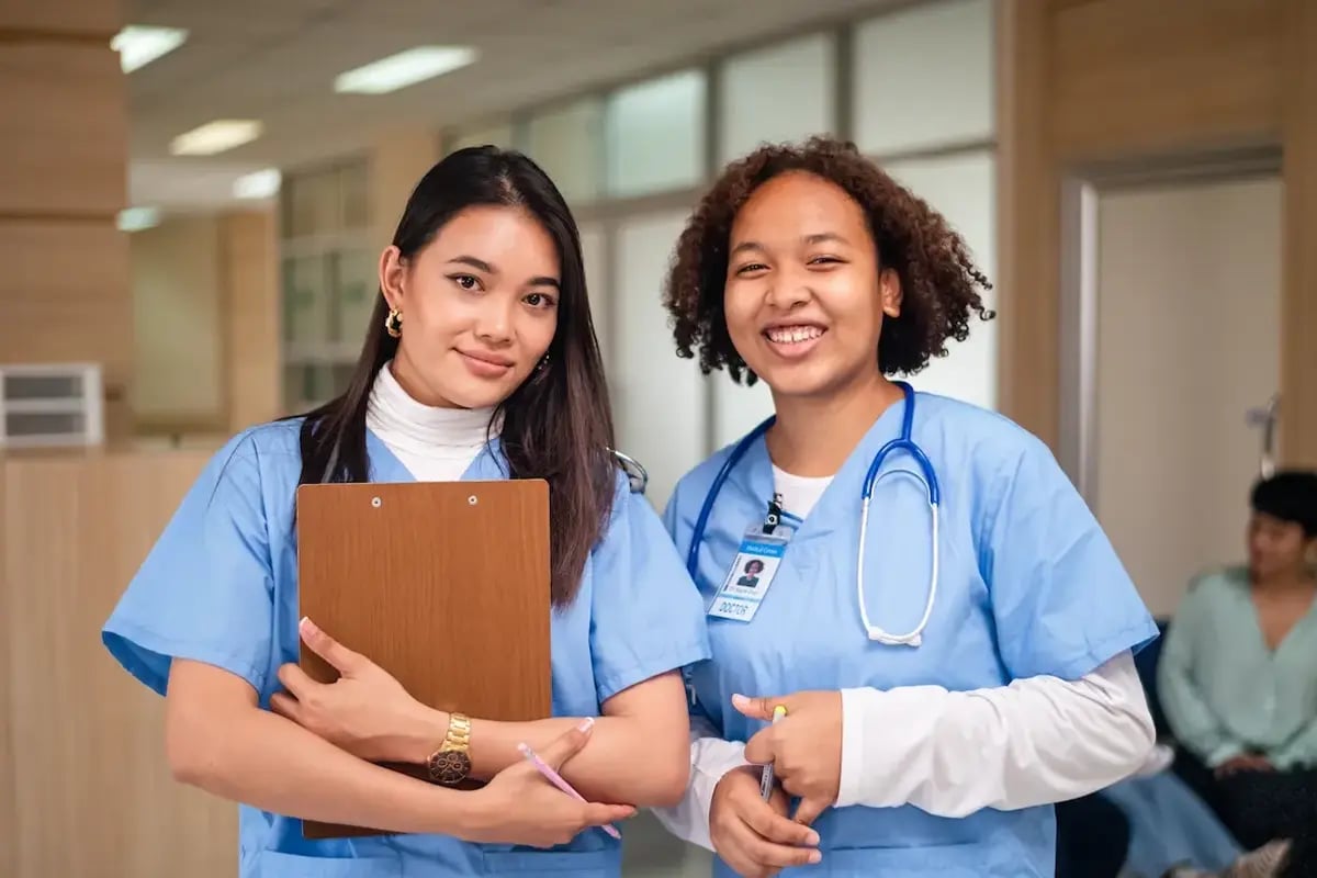 Two RNs smiling while holding a clipboard and pencils Two RNs smiling while holding a clipboard and pencils