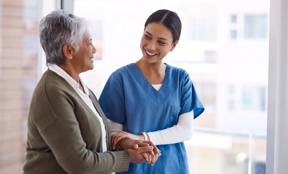 Per diem LPN holding an older patient's arm at the hospital