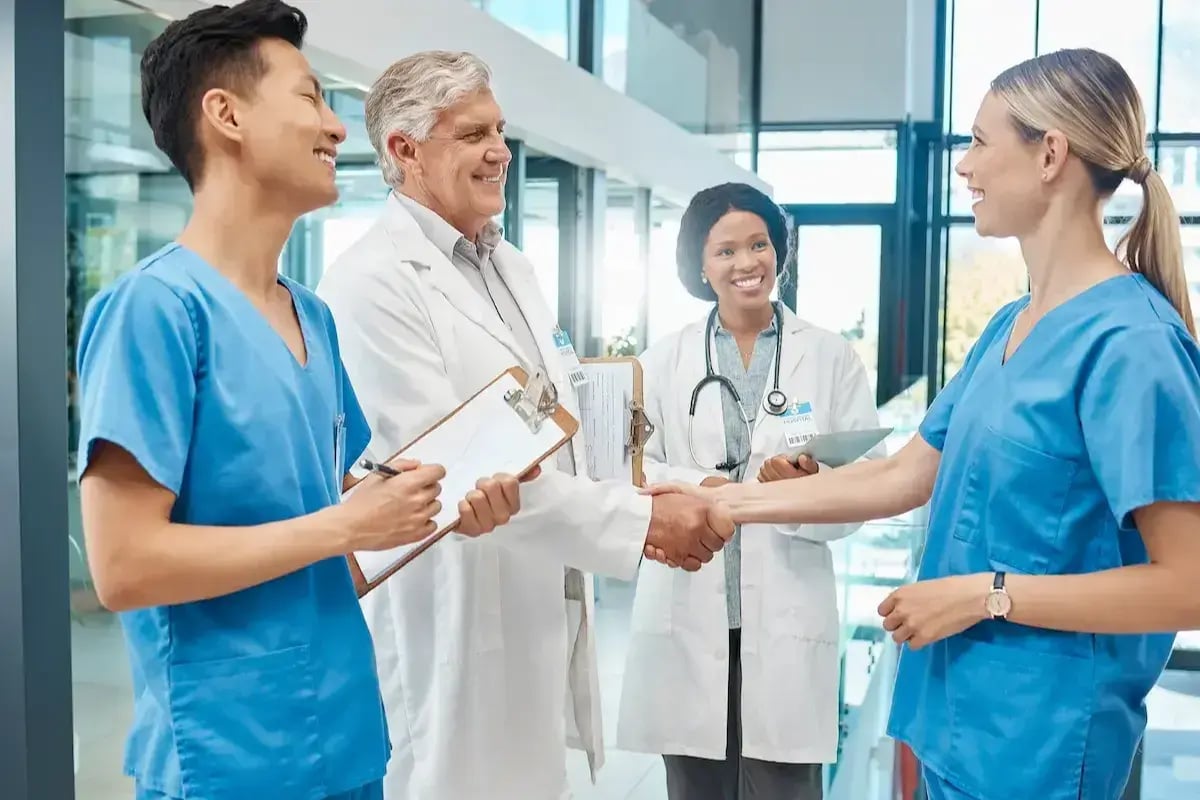 RN nurses on contract chat with doctors in a hospital lobby