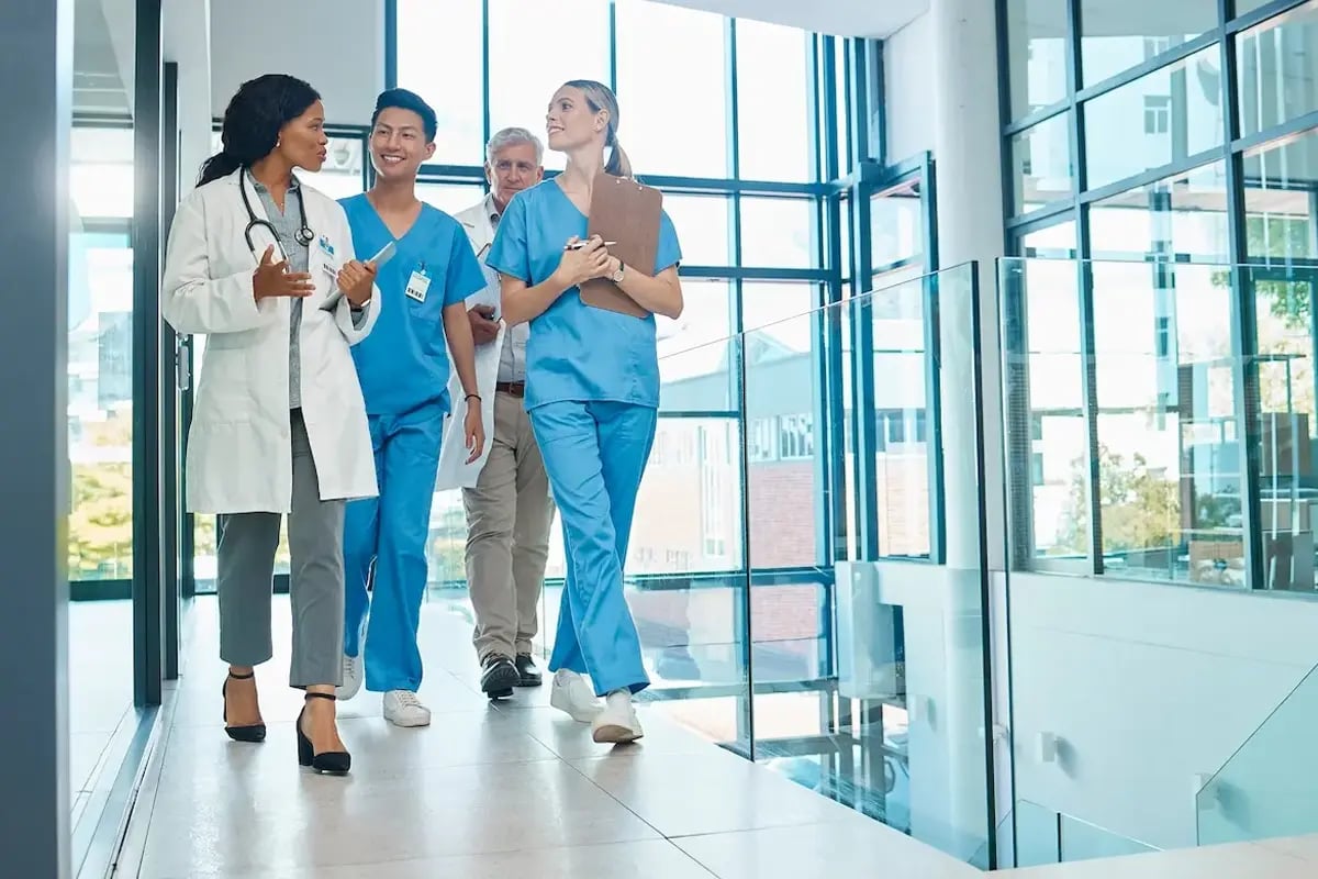 NPs walking and talking with physicians in a hospital lobby