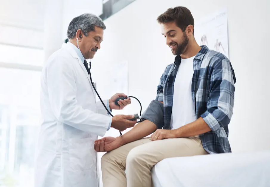Physician taking a young adult male's blood pressure in a doctor's office