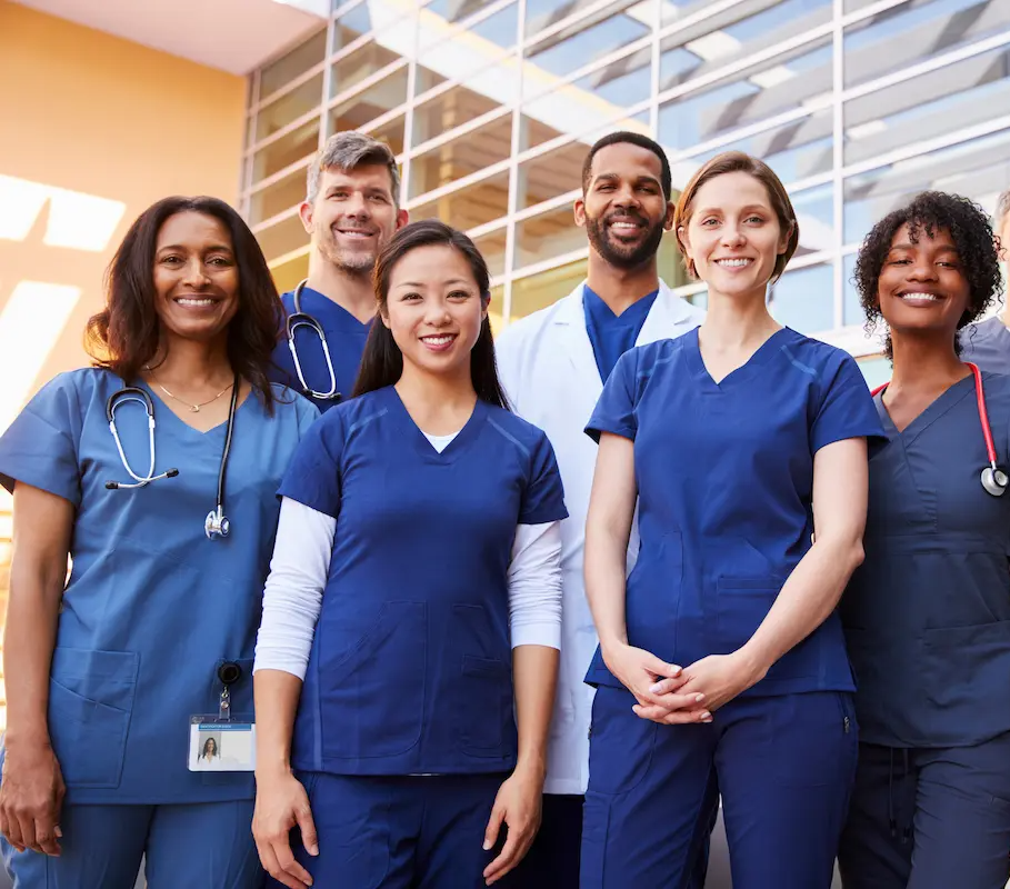 Group of physicians and nurses smiling for a group photo in a hospital lobby
