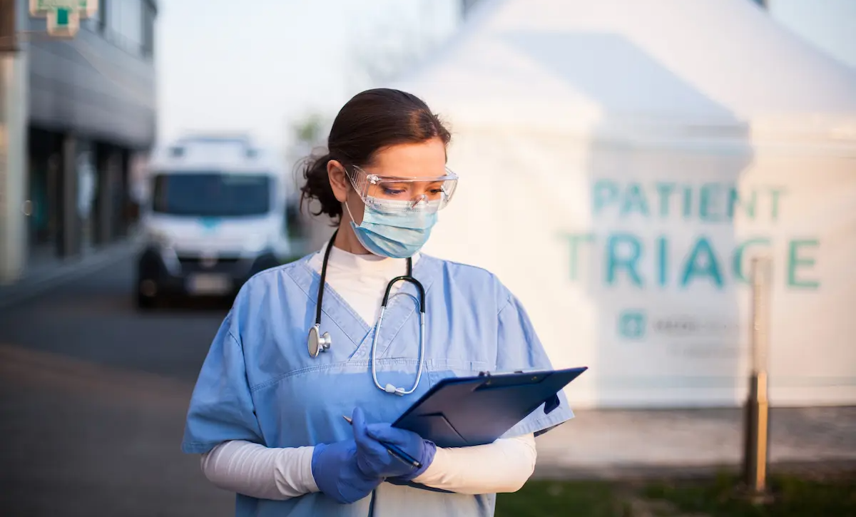 Emergency response RN examining a document outside of a patient triage tent