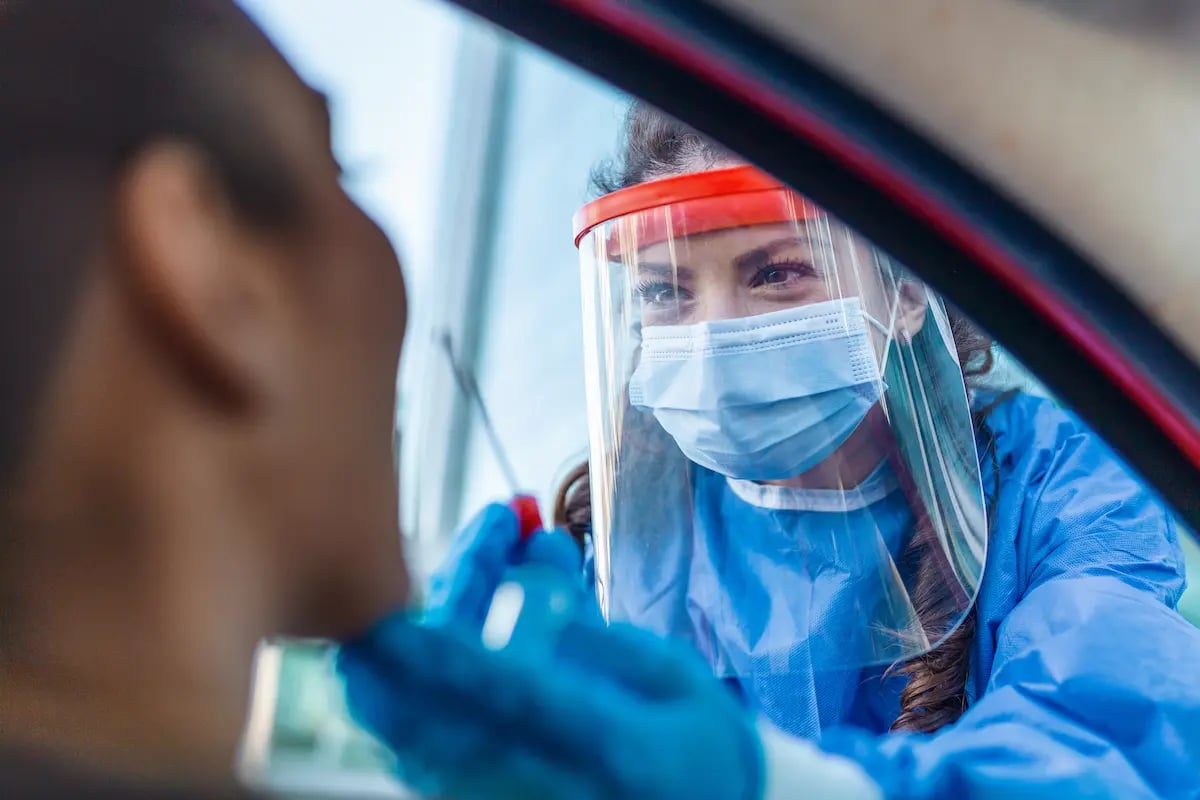 Nurse working the front line giving a drive thru COVID test while wearing a face shield