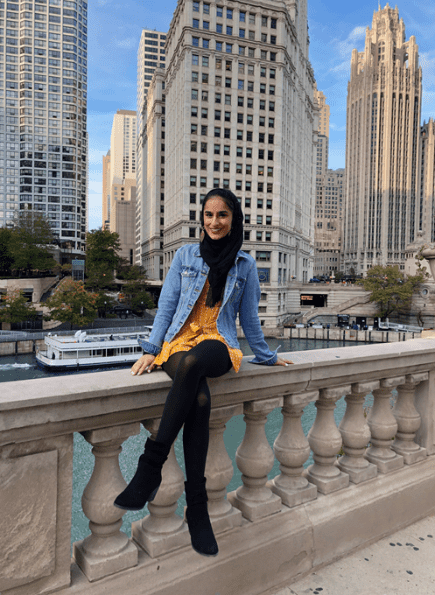 Travel nurse sits on railing near Chicago River in downtown Chicago, Illinois, one of Favorite's Best Places for Travel Nurses