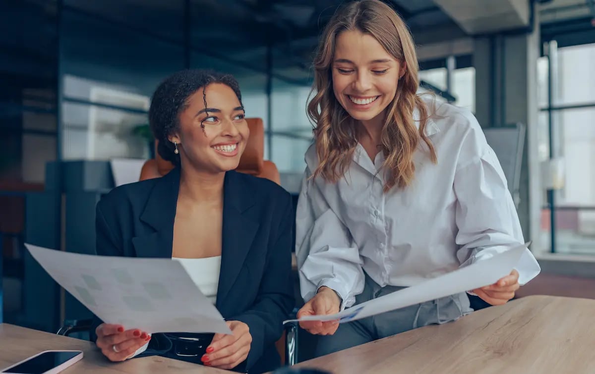 Two businesswomen comparing notes in a meeting room