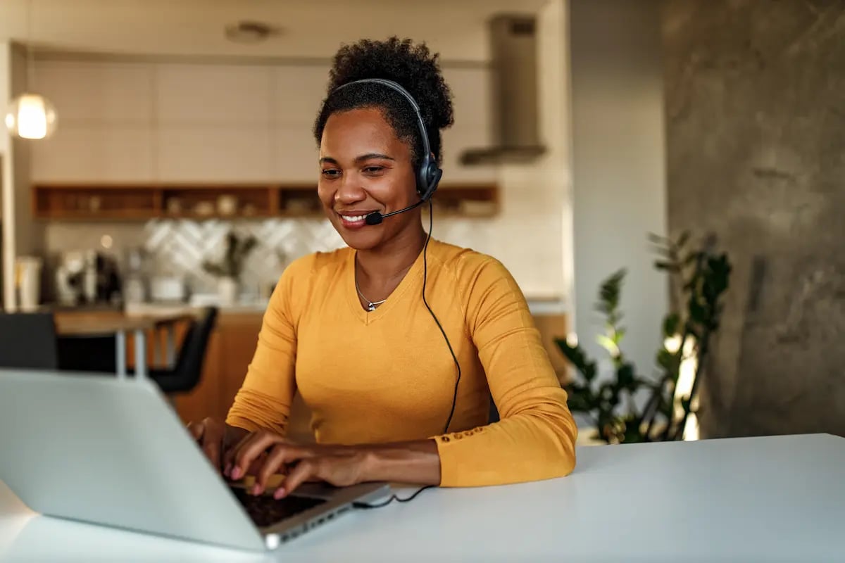 Customer service representative wearing a headset working from home while helping healthcare workers on the phone