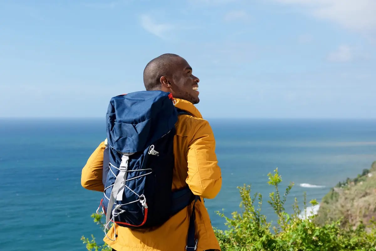 Male travel LPN hiking by the ocean and smiling while on a travel assignment