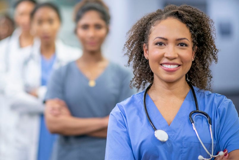 Nurse smiling with other healthcare workers behind them