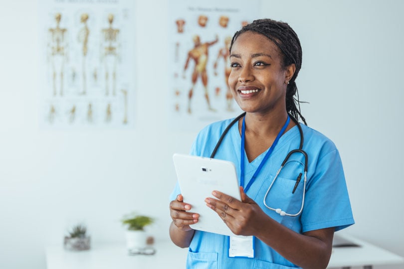 Nurse smiling and holding a tablet while working in a rehabilitation center