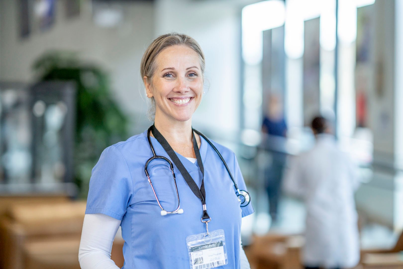 Corrections nurse smiling while working a shift with a physical therapist and patient in the background