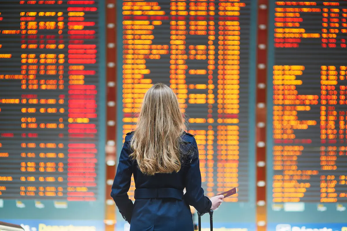 A travel nurse reading the flight times in an airport on her way to an assignment