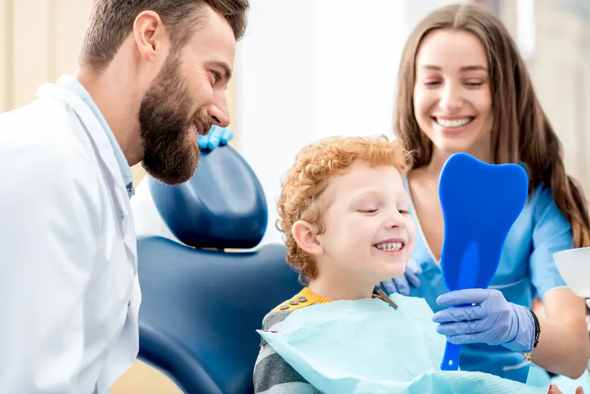 Dentist and dental assistant show a young patient his teeth