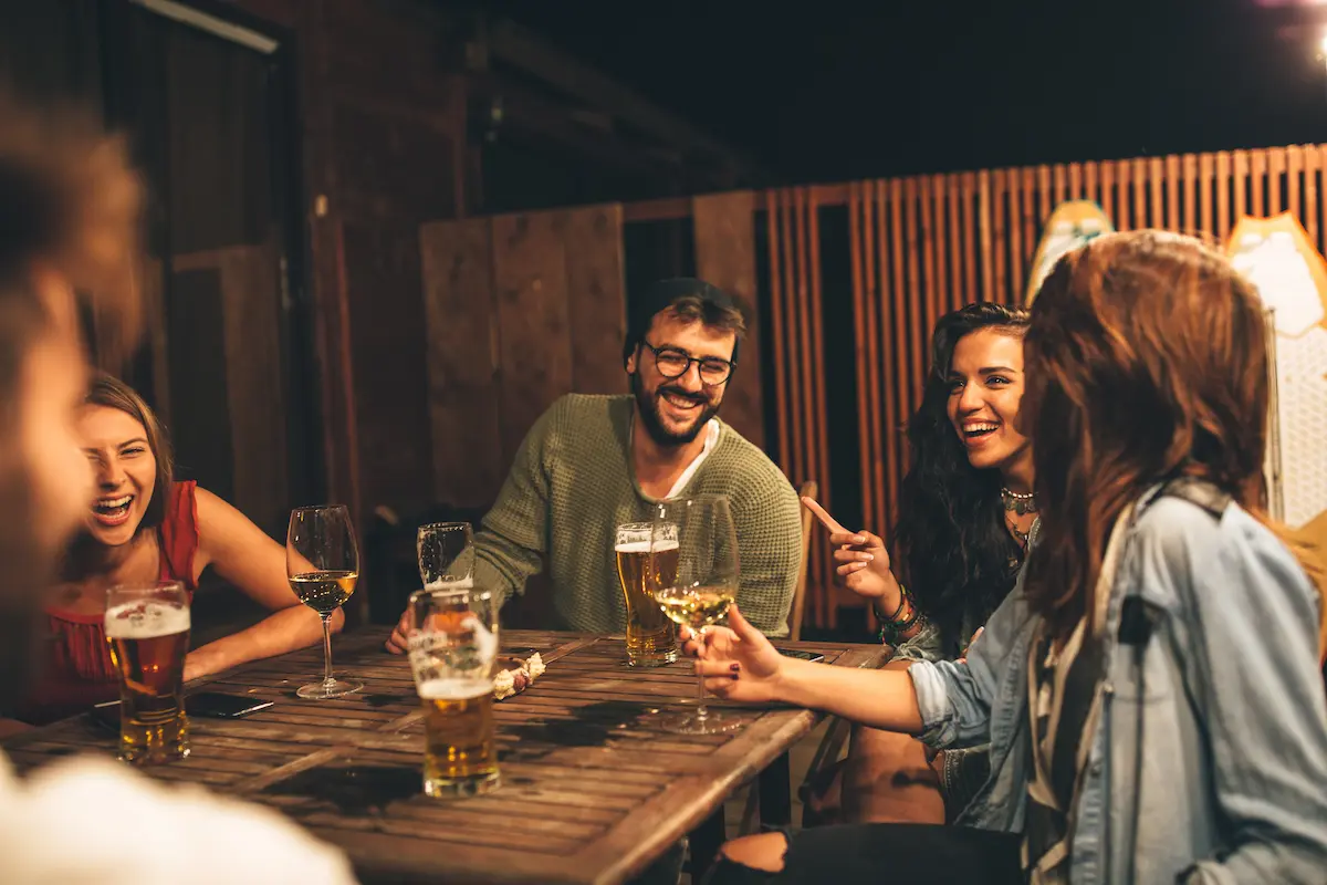 A group of five young adult healthcare professionals sitting at a table conversing with one another over some drinks