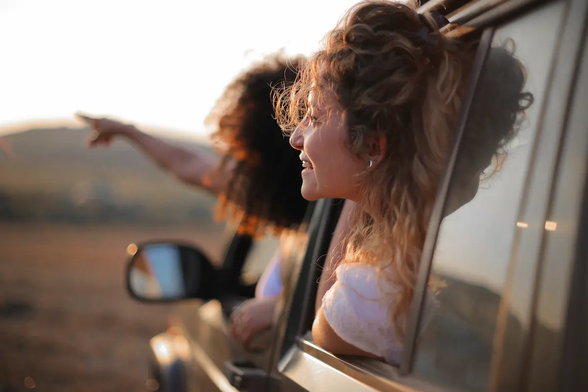 Two travel nurses driving through a desert while looking out the window and pointing at the view