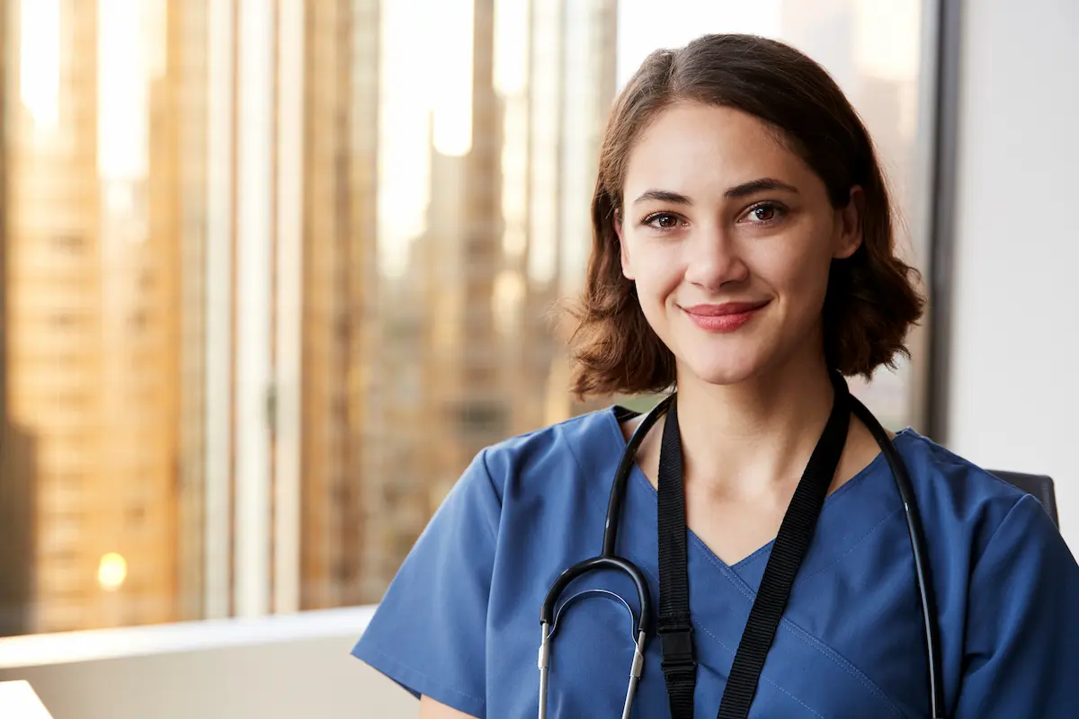 A per diem nurse smiling and standing in front of a window