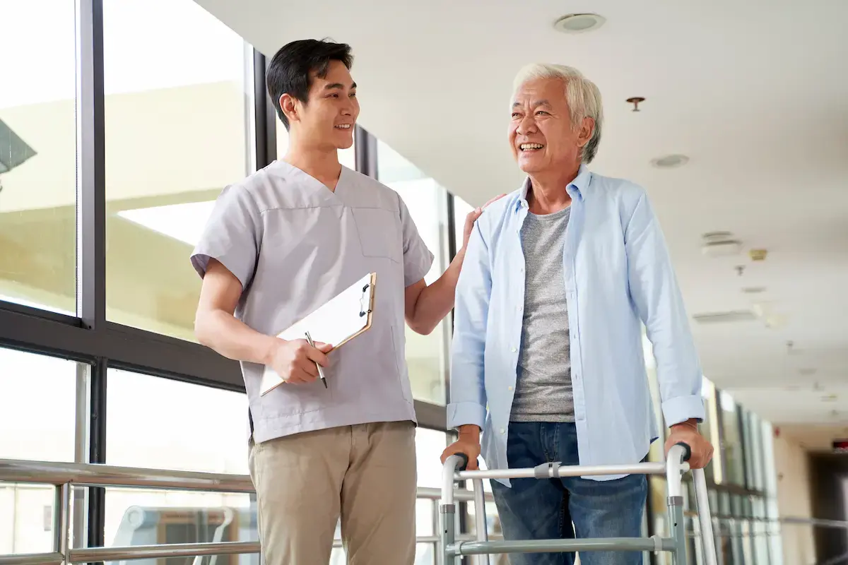 Travel physical therapist helping a patient walk with a walker