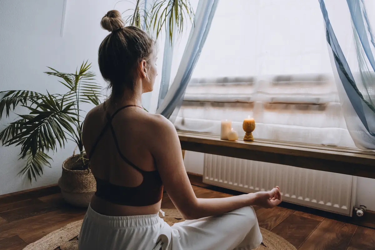 Off duty travel nurse meditating at a window, practicing healthy habits while on a travel assignment