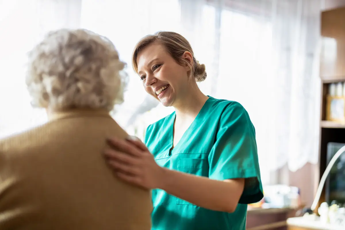 A registered nurse patting an elderly patient on the back