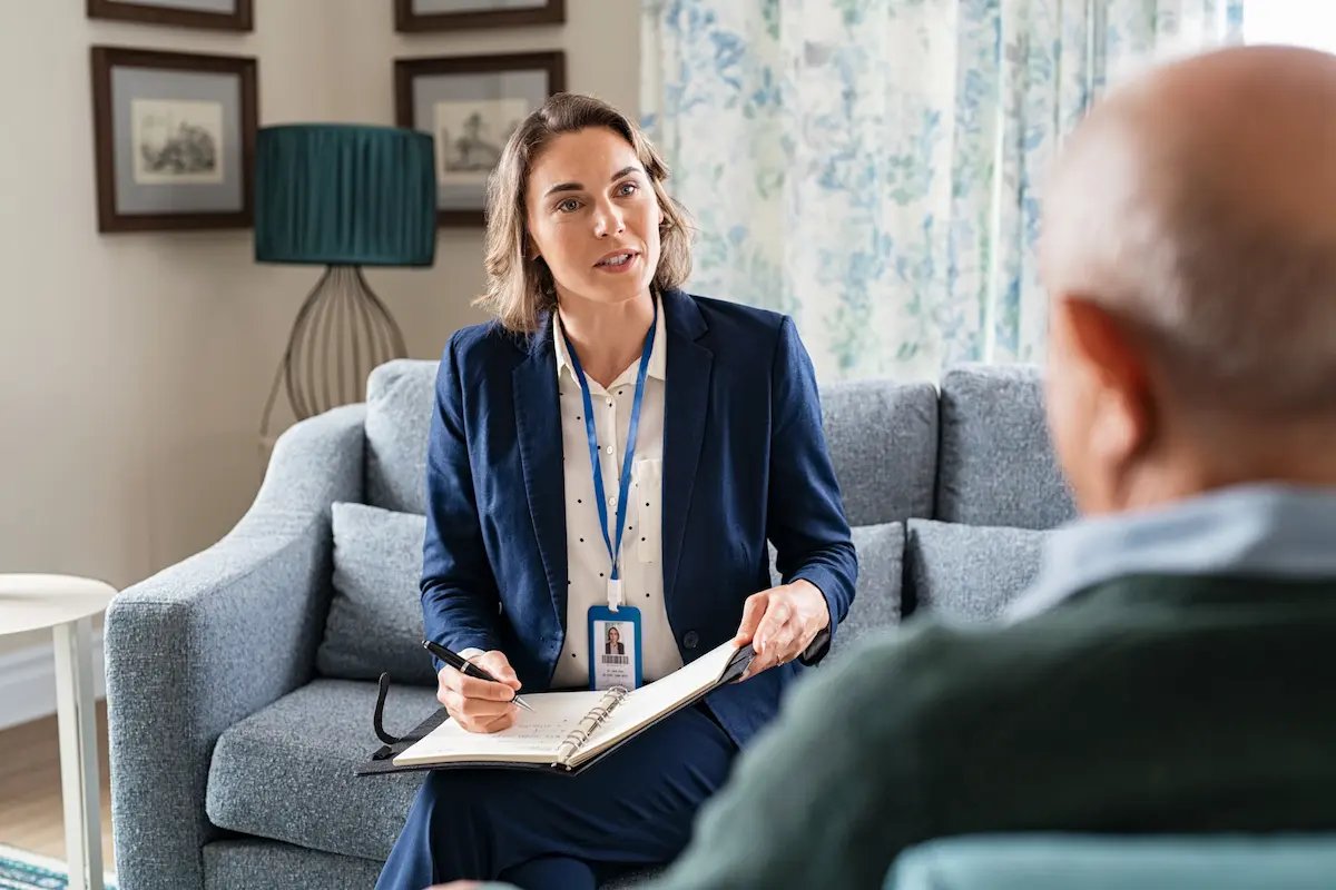 Mental health counselor talking to a older patient on a couch and taking notes