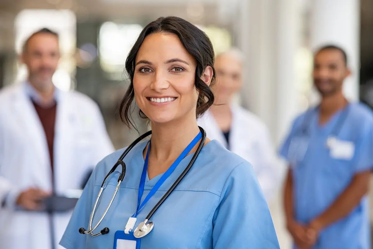 A per diem nurse standing and smiling in front of other nurses and physicians in the background