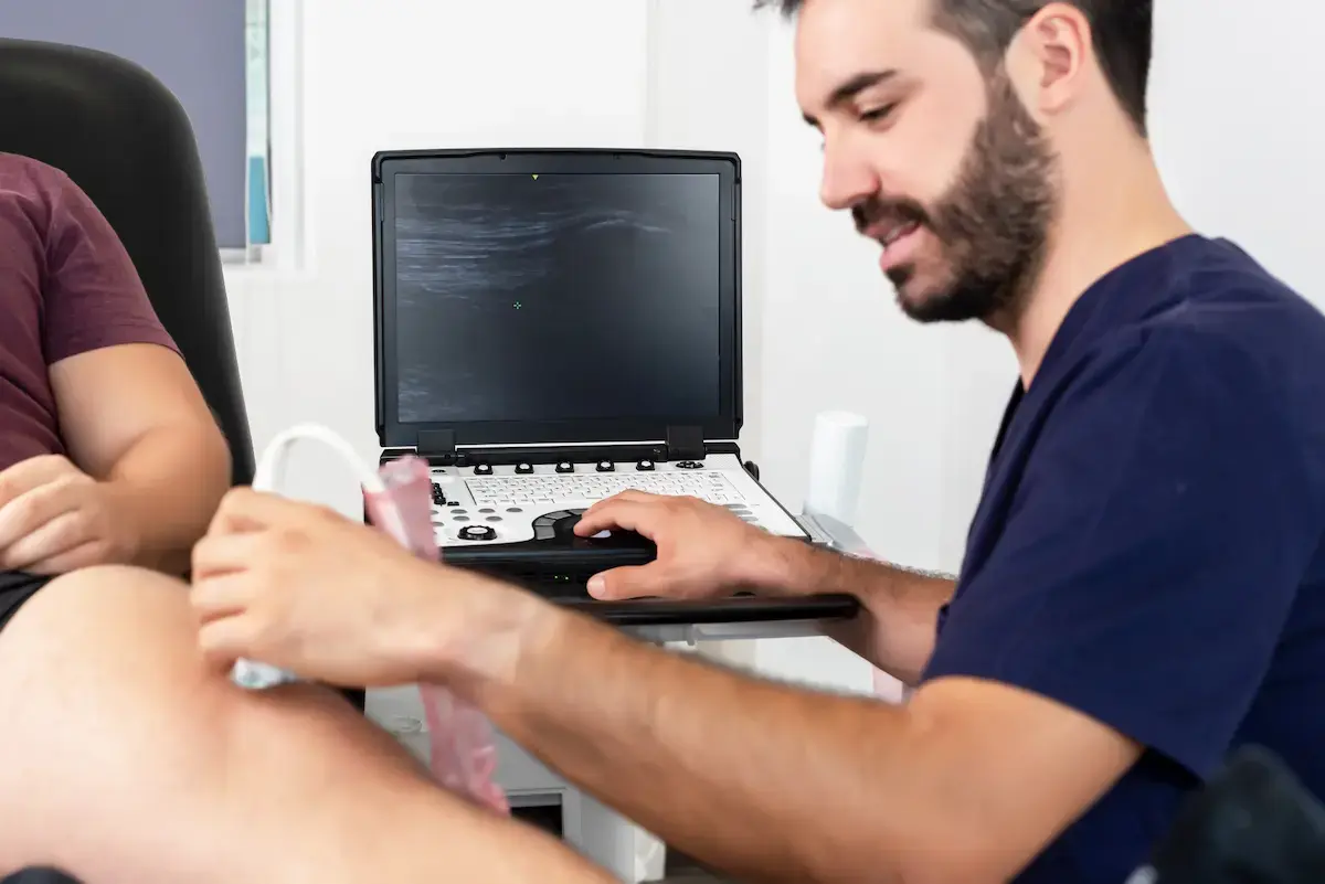 Ultrasound technologist using an ultrasound machine to examine a patient's knee