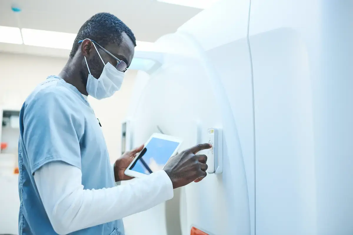MRI technologist turning on a MRI machine with a tablet in his hand