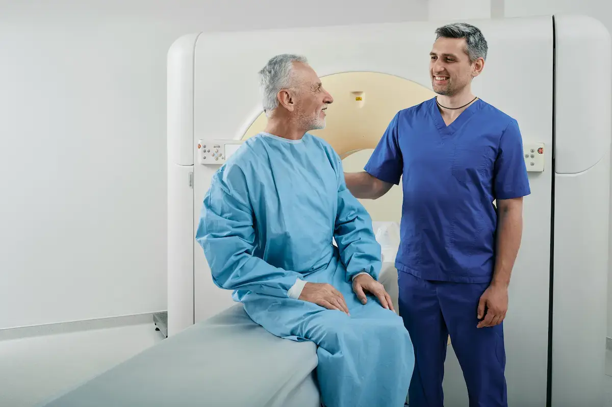 interventional radiology tech helping a man stand up after his MRI