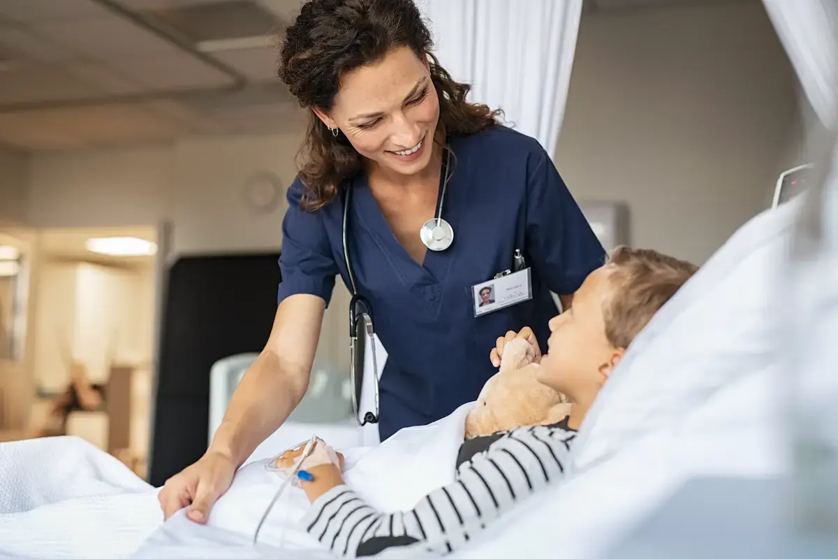 A travel nurse treating a child patient in his hospital room