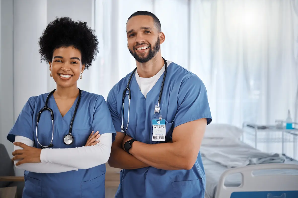 Two per diem nurses standing and smiling with their arms crossed in a patient's hospital room