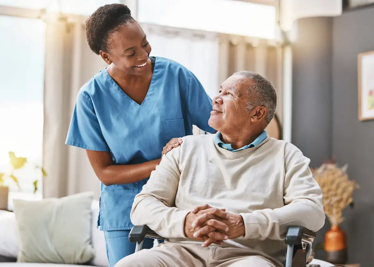 Nurse smiling at an elderly patient in a wheelchair at a nursing home