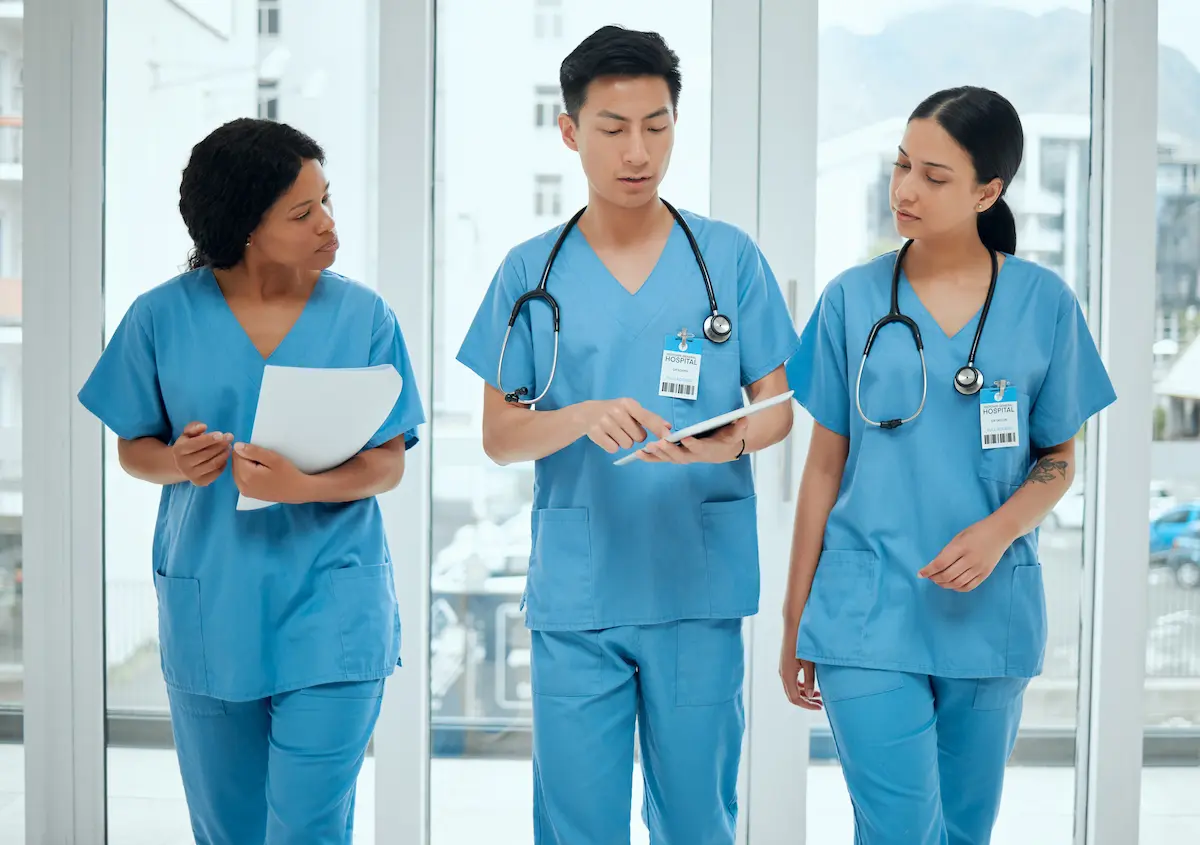 Three nurses walking together in a healthcare facility while having a conversation