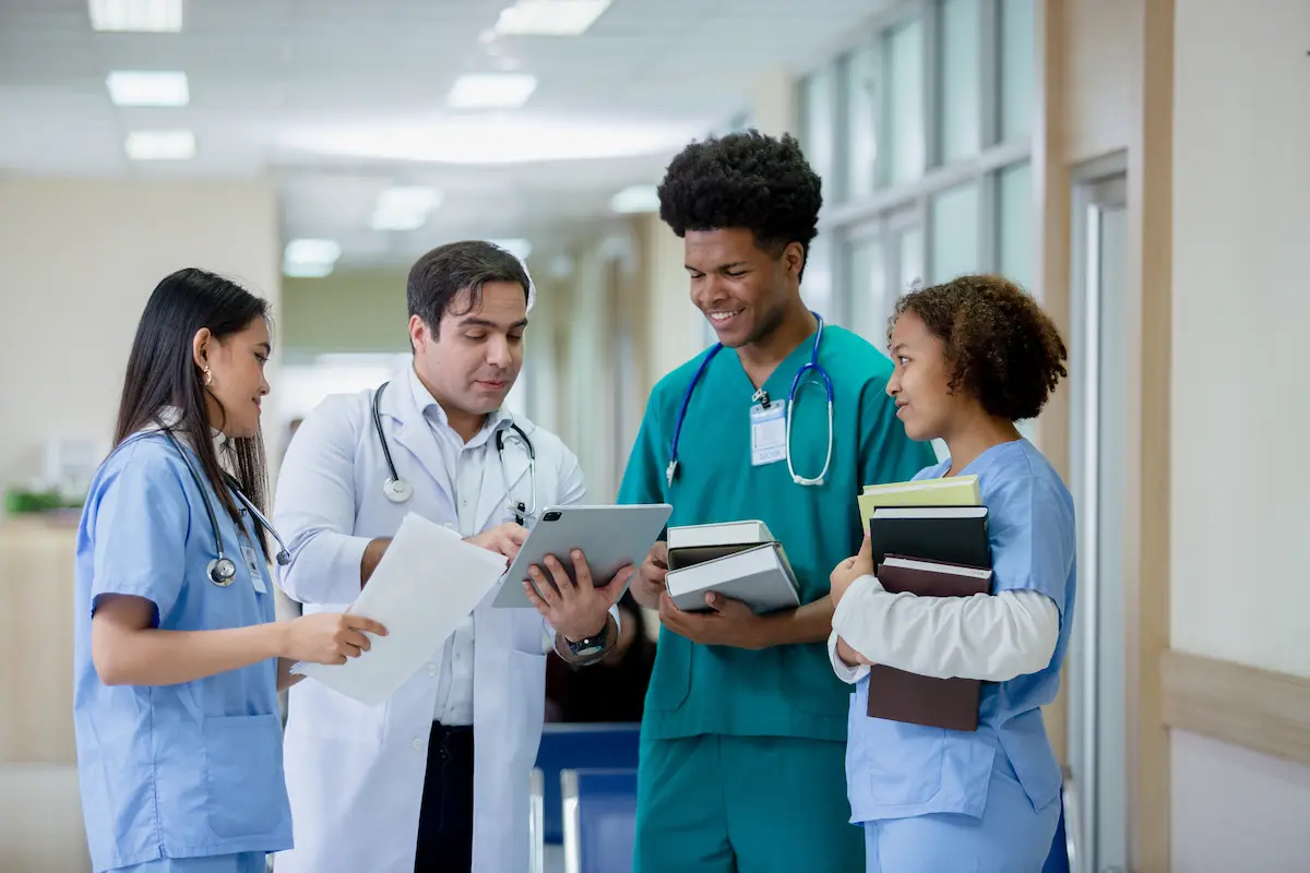 A physician talking to three travel nurses in a hospital