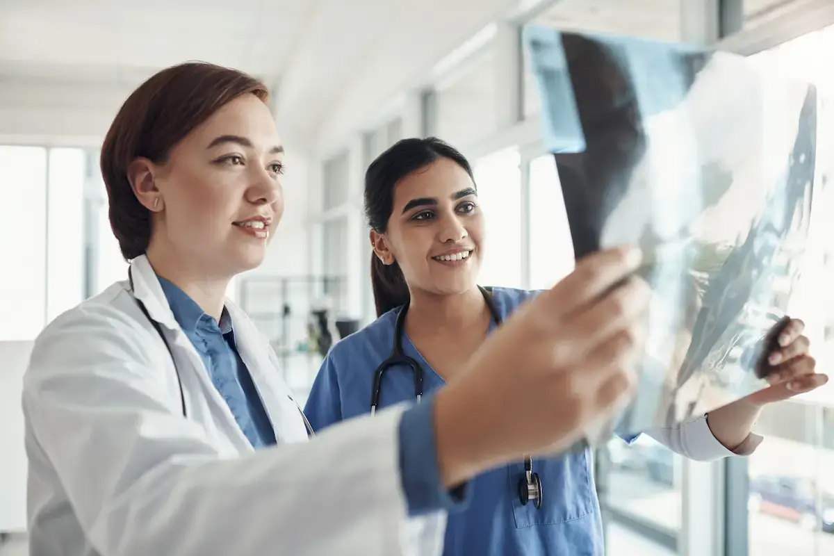 Radiology technologist looks over x-rays with a physician
