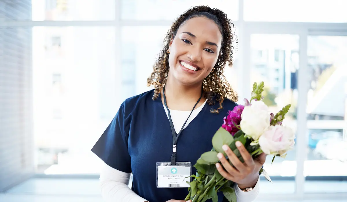 Nurse smiling and receiving flowers for Nurses Week