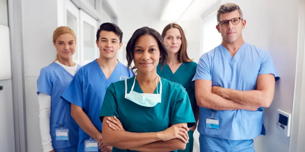 Group of healthcare workers standing in a hospital hallway posing for a picture