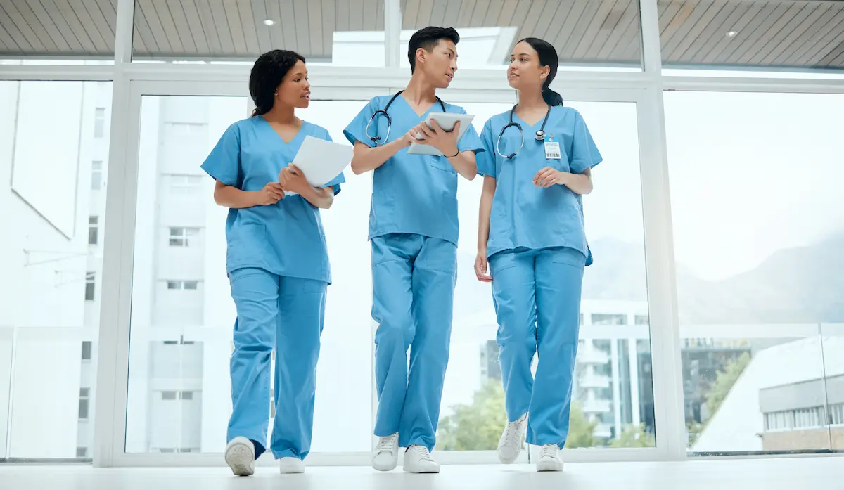 Three nurses walking in a hospital hallway talking to each other