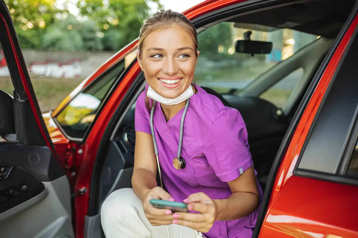 Nurse getting out of a car, using the Mobilize, powered by Favorite Healthcare Staffing app
