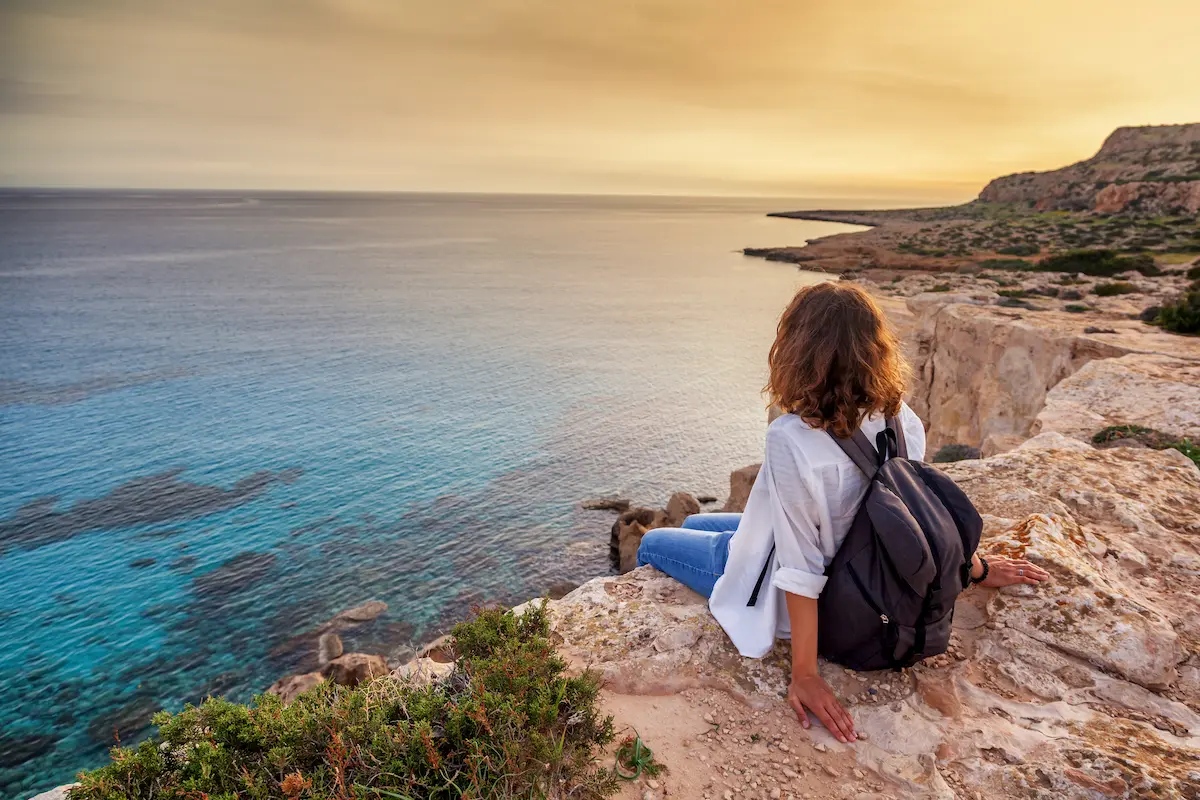 Travel nurse currently on assignment taking a break by sitting on a cliff during sunset
